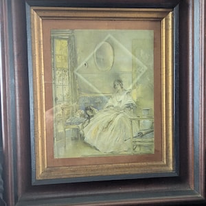 May include: A framed artwork featuring a woman in a long white dress seated on a blue upholstered bench. The artwork is in a gold and brown frame. The scene is set in a room with a window and a mirror.