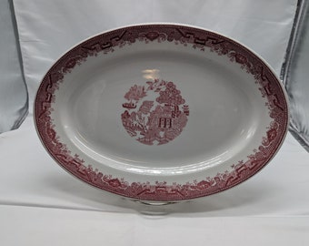 May include: A white oval serving platter with a pink willow pattern design. The pattern features a stylized tree, a house, and a bridge.