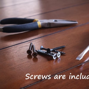 Puede incluir: Un conjunto de herramientas que incluye un destornillador plano, unos alicates y tornillos. El texto "Screws are included" es visible. Las herramientas est&aacute;n dispuestas sobre una superficie de madera.
