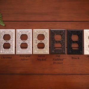 Puede incluir: Una colecci&oacute;n de cubiertas decorativas para enchufes el&eacute;ctricos en varios acabados, incluyendo cromo, plata antigua, n&iacute;quel satinado, bronce aceitado, negro y blanco antiguo. Cada cubierta presenta un dise&ntilde;o floral ornamentado.