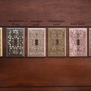 Puede incluir: Seis cubiertas decorativas para interruptores de luz en varios acabados met&aacute;licos: lat&oacute;n, lat&oacute;n reflectante, oro antiguo, oro champ&aacute;n, oro rosa y cobre envejecido. Cada cubierta presenta un dise&ntilde;o floral ornamentado.