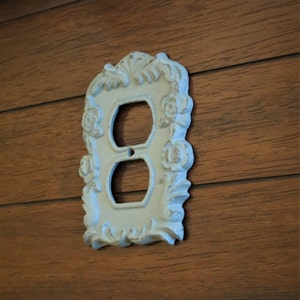 May include: White porcelain outlet cover with a decorative floral design.