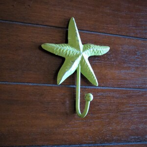 May include: A green metal starfish hook mounted on a wooden wall.