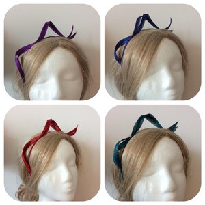 May include: Four headbands in different colors: purple, blue, red, and teal. Each headband is made of a thin, flexible material and has a simple, elegant design.
