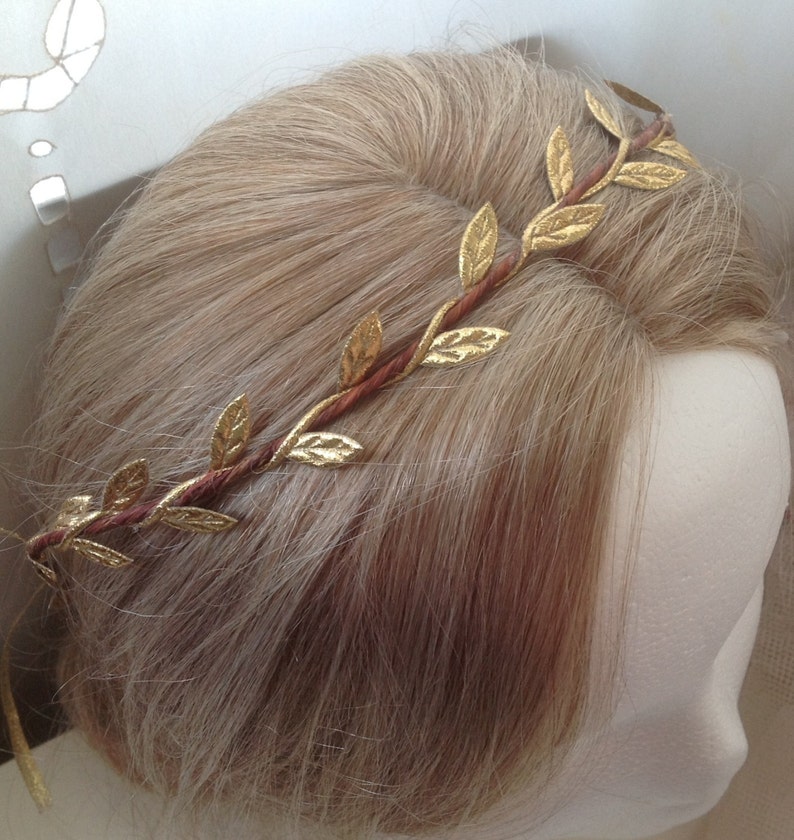 May include: A gold leaf crown with brown wire, worn on a blonde wig.