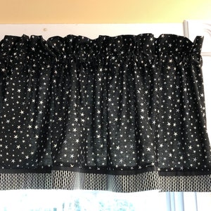 May include: Black and white valance with a white star pattern. The valance has a black and white trim.