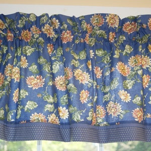 May include: Blue valance with a floral pattern of yellow and orange flowers on a blue background. The valance has a blue and white patterned trim.