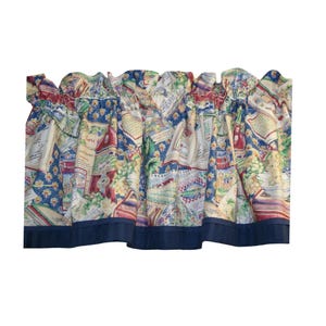 May include: A gathered window valance featuring a multi-colored print of open books, wine bottles, grapes, and French text on a blue background. The fabric is finished with a solid navy blue band along the bottom edge and a rod pocket top.