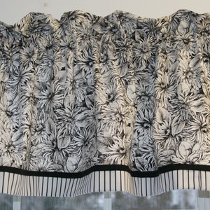 May include: Black and white floral valance with a black and white striped bottom border.