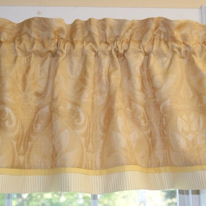 May include: A gold valance with a damask pattern and a yellow and white striped trim.