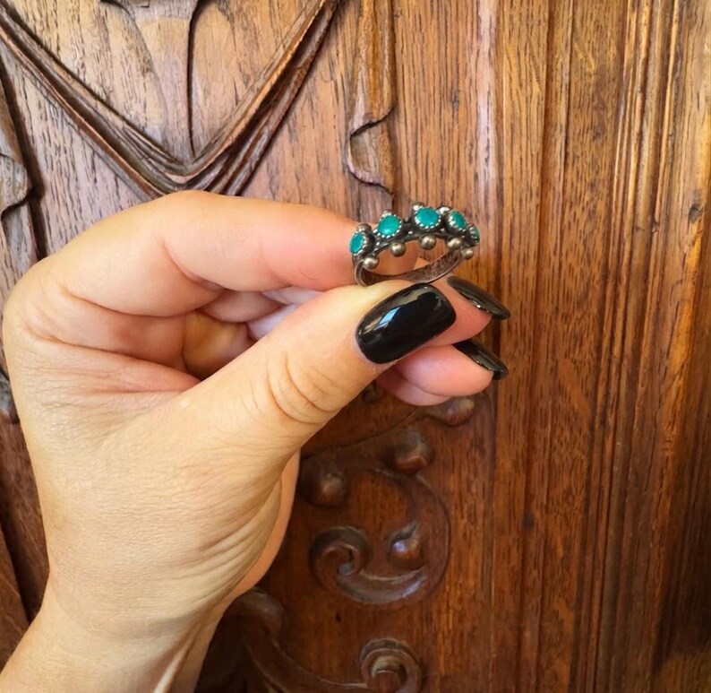 This ZUNI SNAKE EYES RiNG is kinda fabulous.  It came out of a Tucson trading post and is a Fred Harvey era Treasure!  It's sterling and has 5 turquoise snake eyes.  Tiny round raindrops adorn  the sides of the ring.  Size 4-1/2.  Original patina left.

ZUNI SNAKE EYES is a masterful lapidary style originally developed by Zuni Pueblo artists around the 1930s and 1940s. It's one of the most incredibly labor-intensive and meticulous techniques in Native American jewelry making.