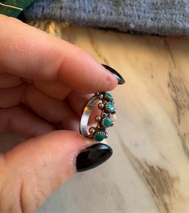 This ZUNI SNAKE EYES RiNG is kinda fabulous.  It came out of a Tucson trading post and is a Fred Harvey era Treasure!  It's sterling and has 5 turquoise snake eyes.  Tiny round raindrops adorn  the sides of the ring.  Size 4-1/2.  Original patina left.

ZUNI SNAKE EYES is a masterful lapidary style originally developed by Zuni Pueblo artists around the 1930s and 1940s. It's one of the most incredibly labor-intensive and meticulous techniques in Native American jewelry making.
