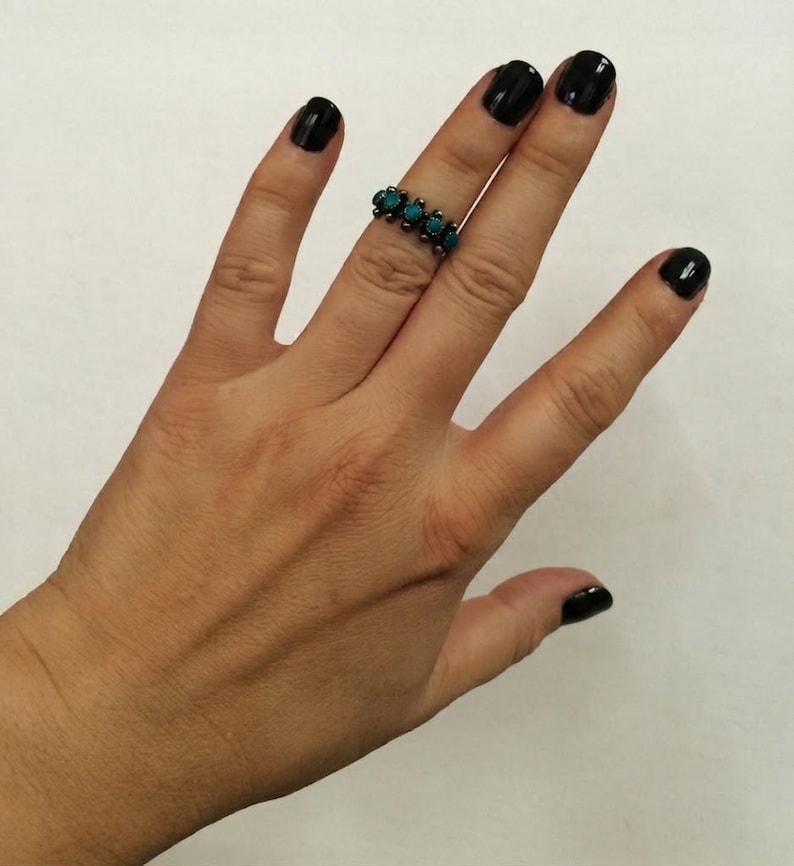This ZUNI SNAKE EYES RiNG is kinda fabulous.  It came out of a Tucson trading post and is a Fred Harvey era Treasure!  It's sterling and has 5 turquoise snake eyes.  Tiny round raindrops adorn  the sides of the ring.  Size 4-1/2.  Original patina left.

ZUNI SNAKE EYES is a masterful lapidary style originally developed by Zuni Pueblo artists around the 1930s and 1940s. It's one of the most incredibly labor-intensive and meticulous techniques in Native American jewelry making.