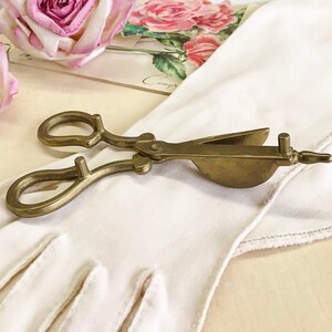 Where can you buy a vintage BRASS CANDLE SNUFFER SciSSors?  Here and it's in GREAT condition and perfect for snuffin' out wicks on candles!  It's so much nicer than burning your fingers. It's FooTeD and has a great gothic or Victorian look and would make a great photography prop.  
I always called this tool a SNUFFER OUTER but did ya know another word for snuffer is Douter?