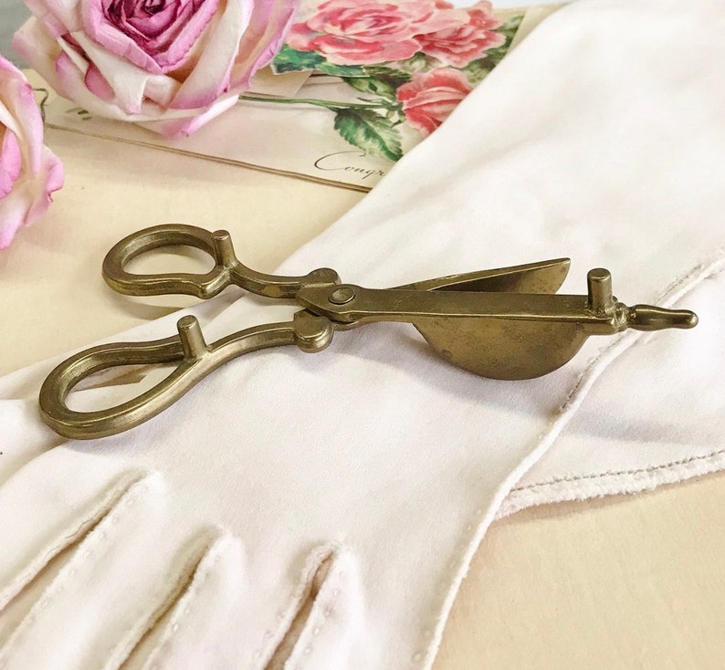 Where can you buy a vintage BRASS CANDLE SNUFFER SciSSors?  Here and it's in GREAT condition and perfect for snuffin' out wicks on candles!  It's so much nicer than burning your fingers. It's FooTeD and has a great gothic or Victorian look and would make a great photography prop.  
I always called this tool a SNUFFER OUTER but did ya know another word for snuffer is Douter?