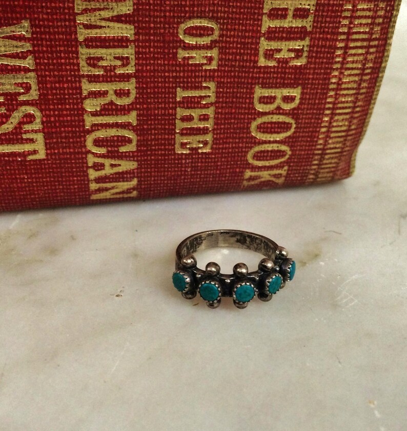 This ZUNI SNAKE EYES RiNG is kinda fabulous.  It came out of a Tucson trading post and is a Fred Harvey era Treasure!  It's sterling and has 5 turquoise snake eyes.  Tiny round raindrops adorn  the sides of the ring.  Size 4-1/2.  Original patina left.

ZUNI SNAKE EYES is a masterful lapidary style originally developed by Zuni Pueblo artists around the 1930s and 1940s. It's one of the most incredibly labor-intensive and meticulous techniques in Native American jewelry making.