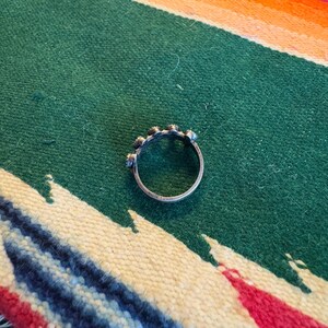 This ZUNI SNAKE EYES RiNG is kinda fabulous.  It came out of a Tucson trading post and is a Fred Harvey era Treasure!  It's sterling and has 5 turquoise snake eyes.  Tiny round raindrops adorn  the sides of the ring.  Size 4-1/2.  Original patina left.

ZUNI SNAKE EYES is a masterful lapidary style originally developed by Zuni Pueblo artists around the 1930s and 1940s. It's one of the most incredibly labor-intensive and meticulous techniques in Native American jewelry making.