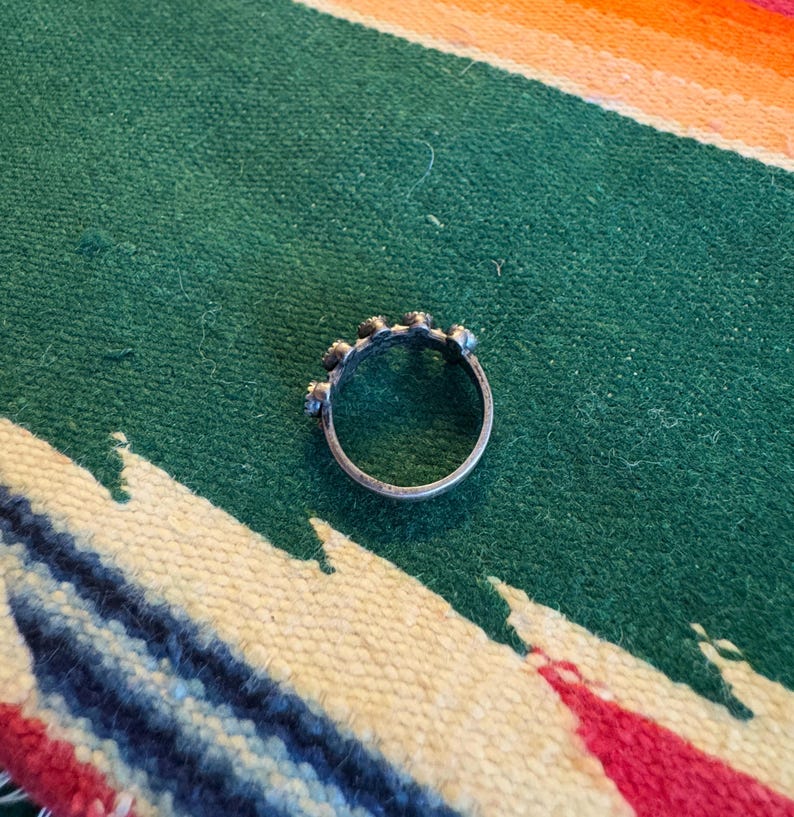 This ZUNI SNAKE EYES RiNG is kinda fabulous.  It came out of a Tucson trading post and is a Fred Harvey era Treasure!  It's sterling and has 5 turquoise snake eyes.  Tiny round raindrops adorn  the sides of the ring.  Size 4-1/2.  Original patina left.

ZUNI SNAKE EYES is a masterful lapidary style originally developed by Zuni Pueblo artists around the 1930s and 1940s. It's one of the most incredibly labor-intensive and meticulous techniques in Native American jewelry making.