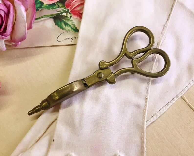 Where can you buy a vintage BRASS CANDLE SNUFFER SciSSors?  Here and it's in GREAT condition and perfect for snuffin' out wicks on candles!  It's so much nicer than burning your fingers. It's FooTeD and has a great gothic or Victorian look and would make a great photography prop.  
I always called this tool a SNUFFER OUTER but did ya know another word for snuffer is Douter?