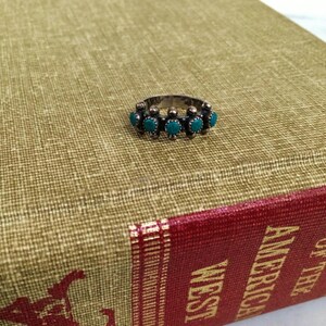This ZUNI SNAKE EYES RiNG is kinda fabulous.  It came out of a Tucson trading post and is a Fred Harvey era Treasure!  It's sterling and has 5 turquoise snake eyes.  Tiny round raindrops adorn  the sides of the ring.  Size 4-1/2.  Original patina left.

ZUNI SNAKE EYES is a masterful lapidary style originally developed by Zuni Pueblo artists around the 1930s and 1940s. It's one of the most incredibly labor-intensive and meticulous techniques in Native American jewelry making.