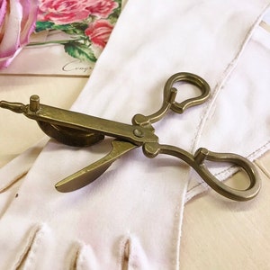 Where can you buy a vintage BRASS CANDLE SNUFFER SciSSors?  Here and it's in GREAT condition and perfect for snuffin' out wicks on candles!  It's so much nicer than burning your fingers. It's FooTeD and has a great gothic or Victorian look and would make a great photography prop.  
I always called this tool a SNUFFER OUTER but did ya know another word for snuffer is Douter?