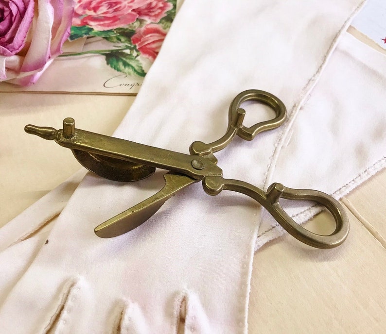 Where can you buy a vintage BRASS CANDLE SNUFFER SciSSors?  Here and it's in GREAT condition and perfect for snuffin' out wicks on candles!  It's so much nicer than burning your fingers. It's FooTeD and has a great gothic or Victorian look and would make a great photography prop.  
I always called this tool a SNUFFER OUTER but did ya know another word for snuffer is Douter?