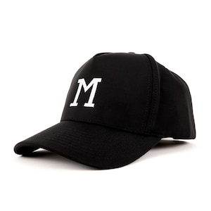 May include: Black baseball cap with a curved peak. The cap displays a white "M" on the front. The hat is made of a smooth material, suitable for casual wear.