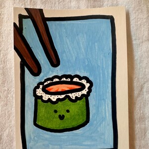 May include: Hand-drawn illustration of sushi roll with a smiling face, green seaweed, and orange filling, set against a light blue background. Brown chopsticks are positioned above the sushi. The artwork is framed with a black border.