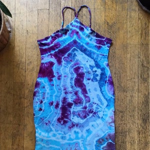 May include: A tie-dye halter dress with a blue and purple swirl pattern. The dress is sleeveless and has a fitted silhouette.