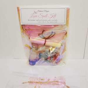 May include: A love spell kit with a pink and white theme. The kit includes a spell scroll, intention candle, love herbs, come to me oil, and a clear quartz crystal. The kit is packaged in a clear plastic bag with a pink and white design.