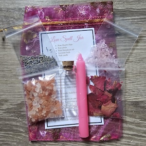 May include: A pink organza bag filled with various ingredients for a love spell jar. The ingredients include rose quartz chips, rose petals, pink Himalayan salt, lavender buds, and a pink candle. The bag is labeled "Love Spell Jar" and lists the ingredients.