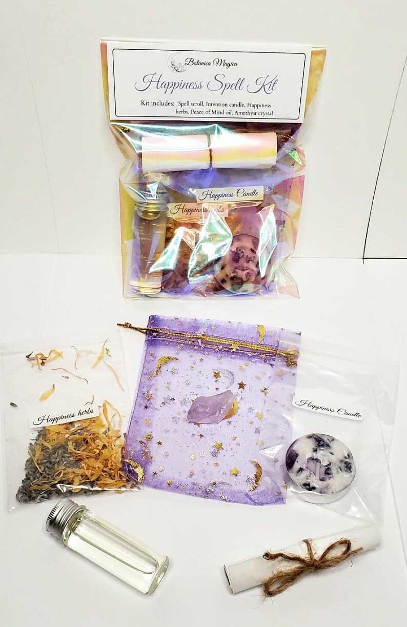 May include: A Happiness Spell Kit with various components, including a spell scroll, intention candle, herbs, oil, and an amethyst crystal. The kit is packaged in clear bags and a purple pouch with gold stars and a moon design. The kit includes a Happiness candle.