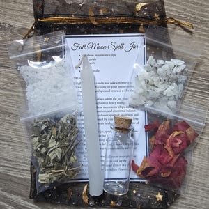 May include: A full moon spell jar kit with instructions. The kit includes a small glass jar, a white candle, moonstone chips, rose petals, dried herbs, and sea salt. The jar is labeled "Full Moon Spell Jar".