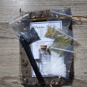 May include: A protection spell jar kit with black tourmaline, sea salt, bay leaf, rosemary, a black candle, and a mini scroll. The kit comes in a black and gold mesh bag.