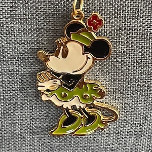 May include: A gold chain necklace with a green and black enamel Minnie Mouse pendant. The pendant features a red flower on her head and a white face.