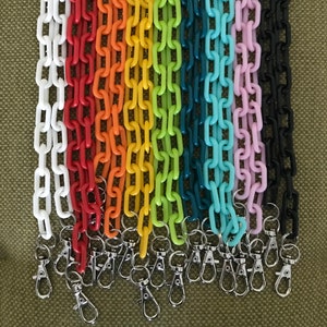 May include: A set of 12 colorful plastic chain straps with silver swivel clasps. The chains are in various colors, including white, red, orange, yellow, green, blue, and black.