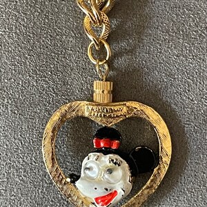 May include: Gold-tone chain necklace with a heart-shaped pendant featuring a cartoon image of Minnie Mouse. The pendant has a textured surface and the text "Walt Disney Productions" is visible on the back.