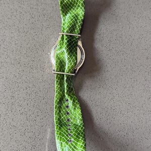 May include: A white ceramic mug with a black handle and the text "But First, Coffee" in a bold, black font. The mug is filled with a dark liquid, likely coffee, and sits on a light-colored surface.