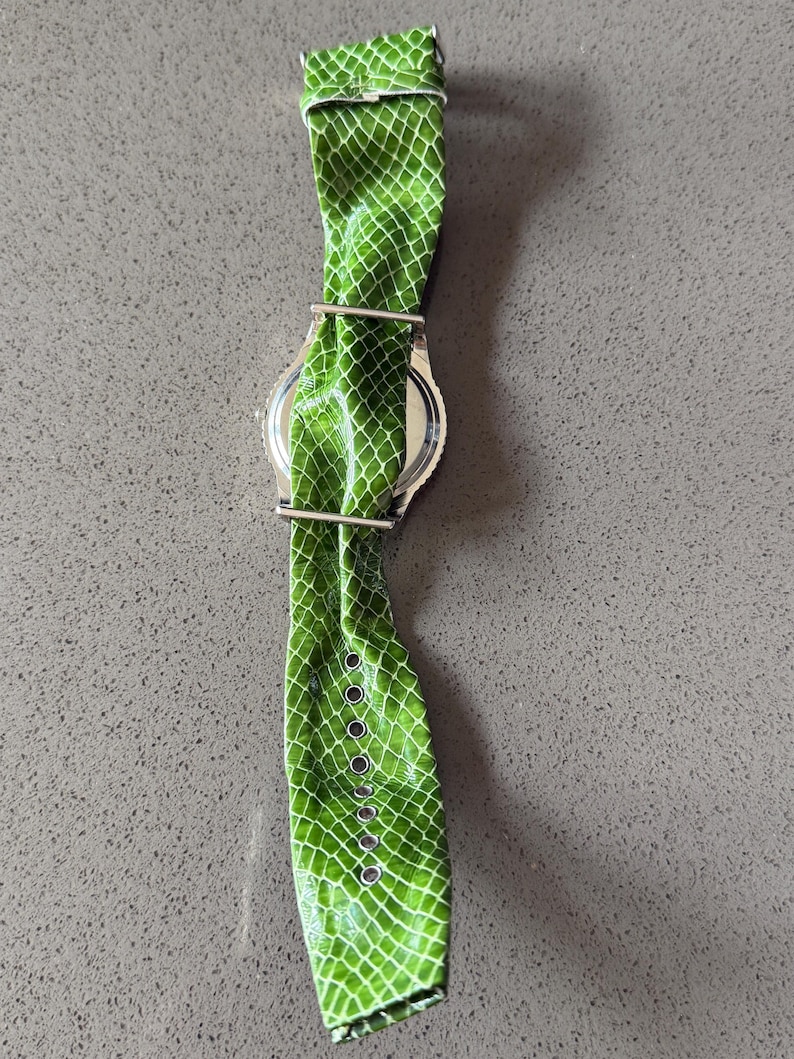 May include: A white ceramic mug with a black handle and the text "But First, Coffee" in a bold, black font. The mug is filled with a dark liquid, likely coffee, and sits on a light-colored surface.