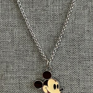 Pu&ograve; includere: Collana color argento con ciondolo di Topolino. Il ciondolo ha un viso color crema, orecchie nere e bocca rossa. La catena &egrave; un design delicato e collegato, creando un accessorio classico e riconoscibile.