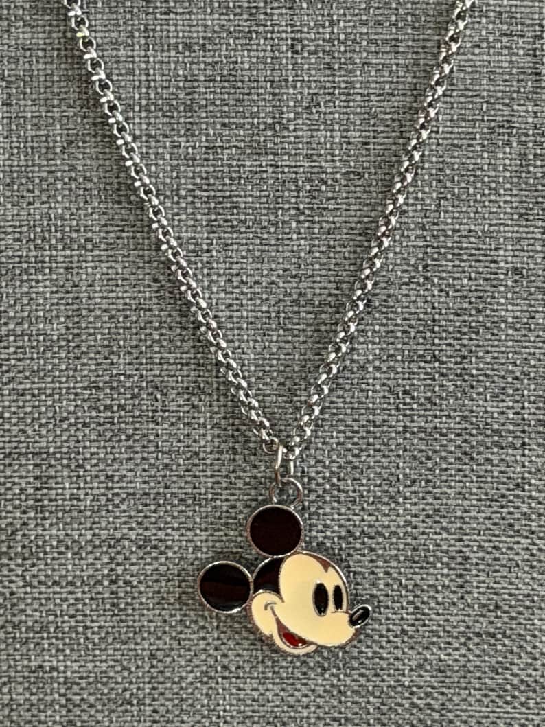 Pu&ograve; includere: Collana color argento con ciondolo di Topolino. Il ciondolo ha un viso color crema, orecchie nere e bocca rossa. La catena &egrave; un design delicato e collegato, creando un accessorio classico e riconoscibile.
