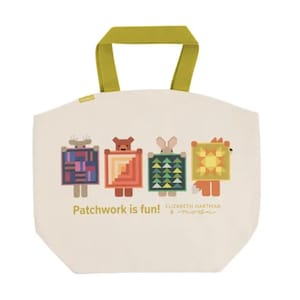 Peut inclure: Sac fourre-tout crème avec une poignée verte. Le sac présente quatre personnages d'animaux de dessins animés tenant des motifs de patchwork colorés. Le texte sur le sac se lit "Patchwork is fun!" et "Elizabeth Hartman & moda."