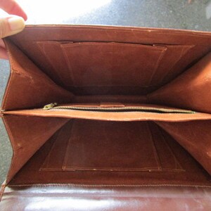 May include: The inside of a brown leather briefcase with multiple compartments and a zippered pocket.