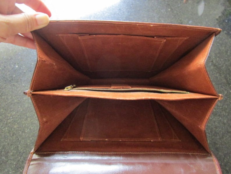 May include: The inside of a brown leather briefcase with multiple compartments and a zippered pocket.