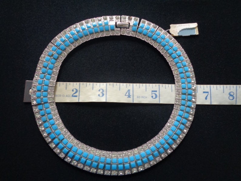 Puede incluir: Un collar de color turquesa y tono plateado con un dise&ntilde;o cuadrado. El collar mide 12,7 cm de di&aacute;metro.
