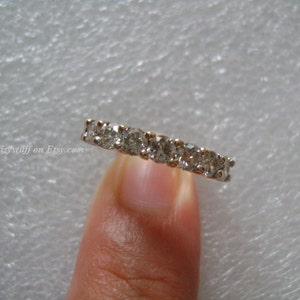 May include: A silver band ring with a row of small, clear round diamonds.
