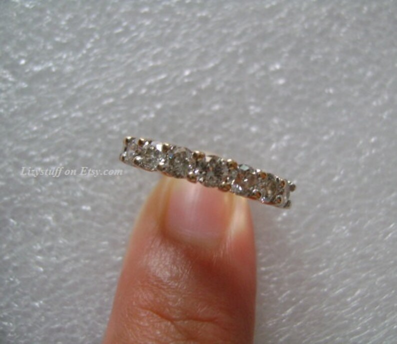 May include: A silver band ring with a row of small, clear round diamonds.