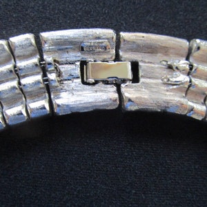 Puede incluir: Collar de metal plateado con un cierre que dice "BERNARD 1".