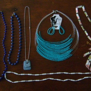 May include: A collection of necklaces and earrings. The necklaces are made of various materials, including beads, turquoise, and white ceramic. The earrings are turquoise and silver.
