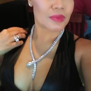 Op de afbeelding: Een zilveren slangenketting met een diamant-achtig ontwerp. De ketting wordt gedragen door een persoon met een zwart topje.